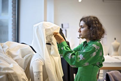 A student works on draping a garment in a fashion studio.
